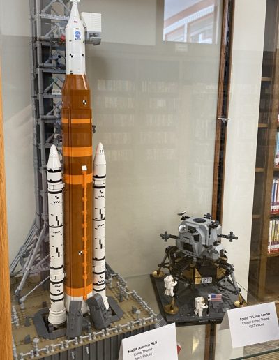 Collection of Lego space vehicles, including rockets and shuttles, on display.