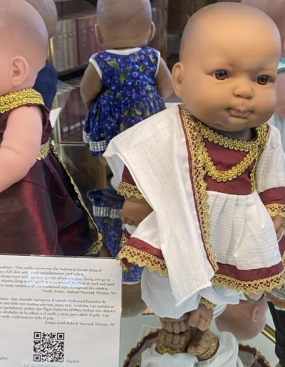 Display case showing a doll wearing traditional clothing