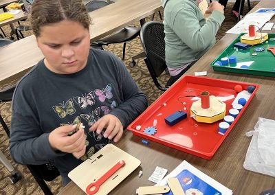 A group of children engaged in crafting activities at a table, focusing on a STEAM project together.