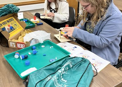 Two girls are seated at a table, diligently working on a STEAM project, in deep concentration.