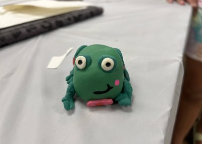 A green clay frog resting on a table, highlighting its charming design and smooth texture.