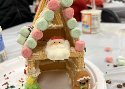 A festive gingerbread house adorned with a Santa Claus figure and a beautifully decorated Christmas tree.