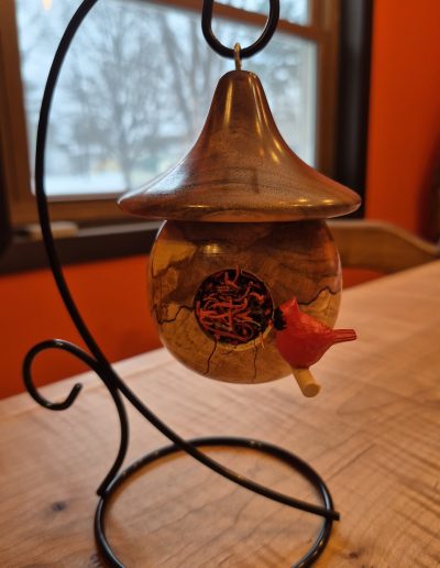 A decorative bird feeder on a metal stand with a red bird figurine.